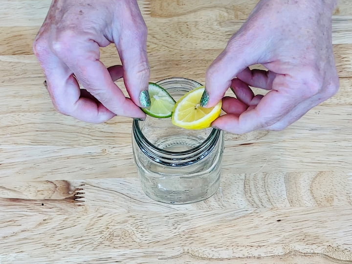 Cut lemons and limes into slices and place them at the base of a mason jar.