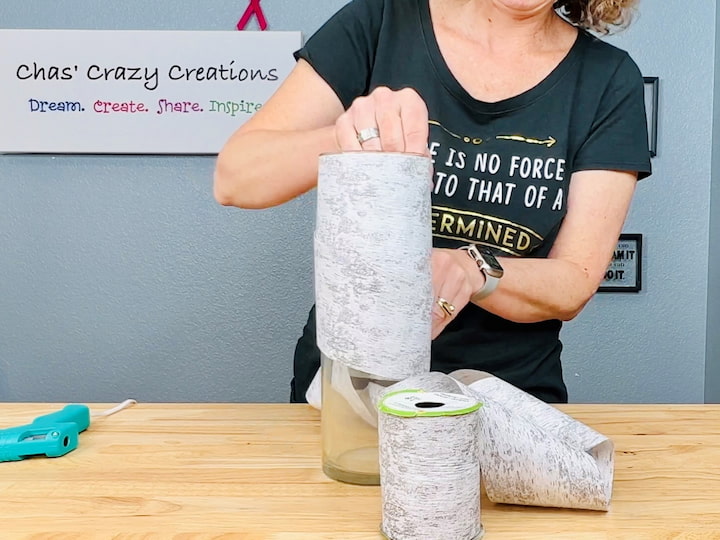 Obtain birch ribbon from Dollar Tree (and you could pick any ribbon, I'm just using birch)  Take a vase you already have at home and apply hot glue to the top.  Wrap the entire vase with the birch ribbon, giving it the appearance of a birch or aspen log.  