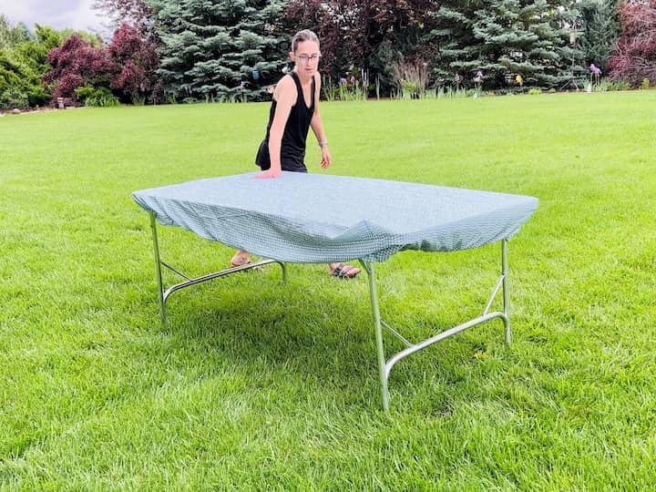 Start by placing a tablecloth on your table. To keep it in place, grab some Dollar Store clips and secure them around the table's edges. Another alternative is using a fitted sheet that fits snugly onto the table, providing a clean and secure surface for your party or barbecue.
