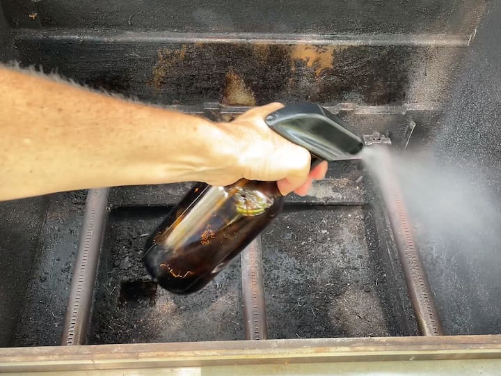 Applying Vinegar: To tackle stubborn residue on the Weber grill, we filled a squirt bottle with vinegar and sprayed it all over the grill grates. After letting it soak for a while, the acidity in the vinegar helps loosen the grime.