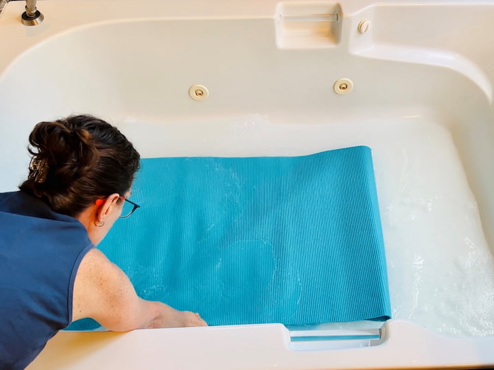For a more thorough cleaning, give your Lululemon yoga mat or regular yoga mat a bath to remove dirt and grime. Add warm water to the bottom of your bathtub and mix it with some Castile soap. You won't see a lot of bubbles, and that is okay.  Place your yoga mat into the bathtub, let it soak for 10 minutes, and wipe it with a sponge or damp cloth. Rinse it off when done, and use a towel to wipe it dry. Avoid hanging your yoga mat in direct sunlight, as UV rays can degrade it.