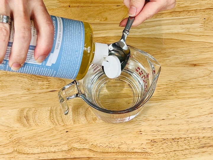 For our first cleaning spray, you'll only need a couple of ingredients. You'll need a cup of water and one tablespoon of pure Castile soap. Mix the water and Castile soap together in a measuring cup or bowl, then pour the mixture into a spray bottle.