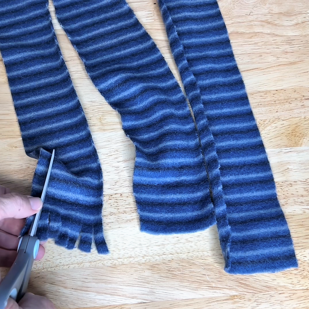 Cut three strips of fabric, ensuring they are long enough to wrap around the candles. Create little fringes at the bottom of each fabric strip by cutting small vertical slits.