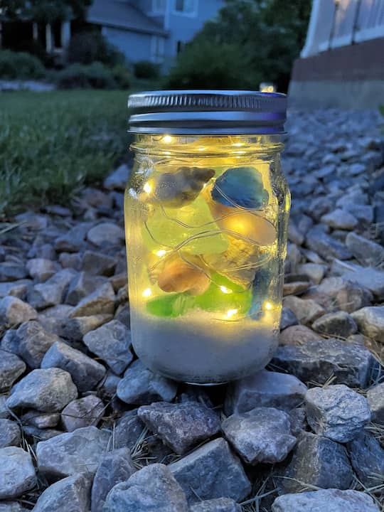 For a beachy vibe, add sea glass and shells around the sand and lights inside the jar. Alternate between layers of lights, sea glass, and shells until the jar is filled to your liking.