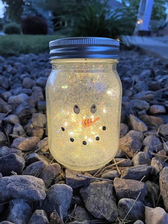 Create a frosty effect by swirling Pledge floor cleaner inside the jar, coating the entire surface. Add a touch of white glitter for a snowy sparkle. Once dry, draw a winter-themed face on the jar with Sharpie markers. Seal it with dishwasher safe Mod Podge or outdoor acrylic paint for durability.
