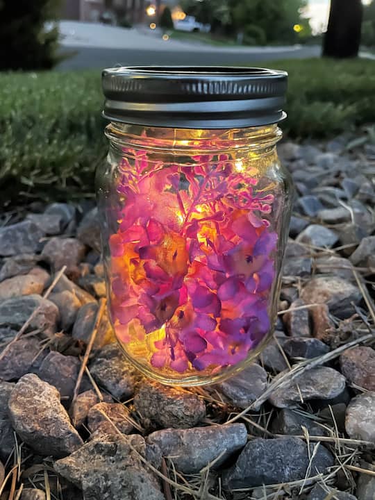 Arrange the fairy lights in the center of the jar without unwinding them too much. Add fake lilacs or other spring flowers around the lights, creating a delightful springtime decoration.