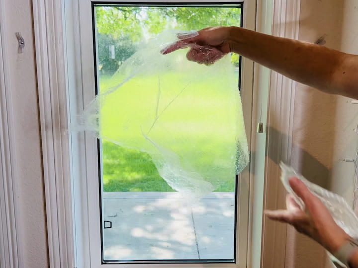 Spray your window with water or rubbing alcohol.Apply bubble wrap to the moistened window; it will stick in place.Optionally, use painter's tape for added support.