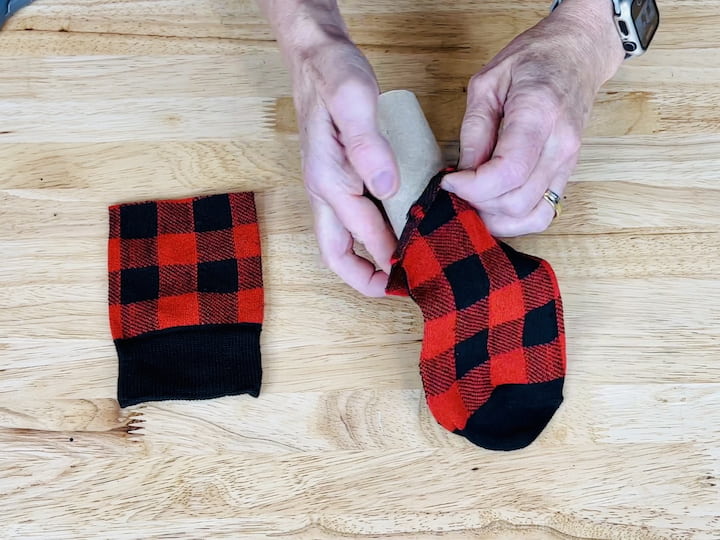 Insert the toilet paper or paper towel tube into the bottom of the sock and tuck any excess fabric into the center of the tube.