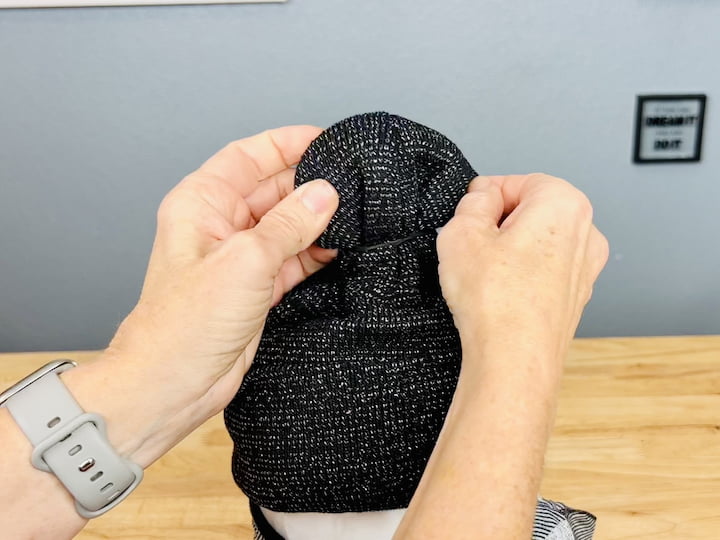 Create a little ball on top of the hat using a rubber band.