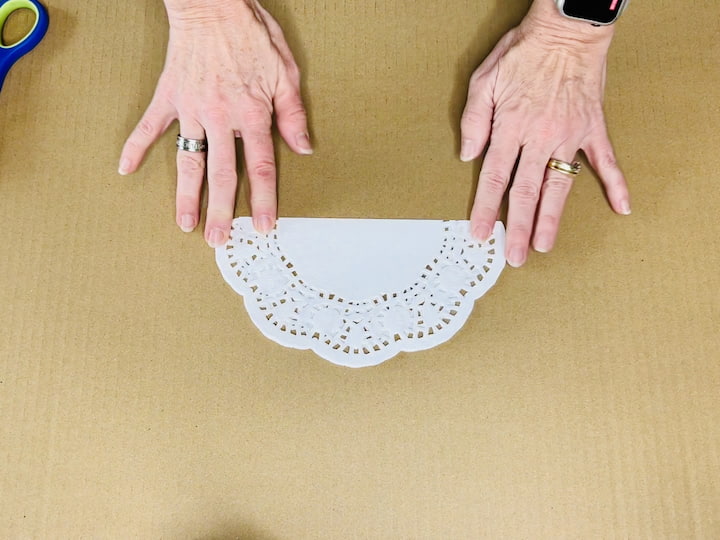 Begin by folding the doily in half. Repeat the folding process two more times, for a total of three folds.