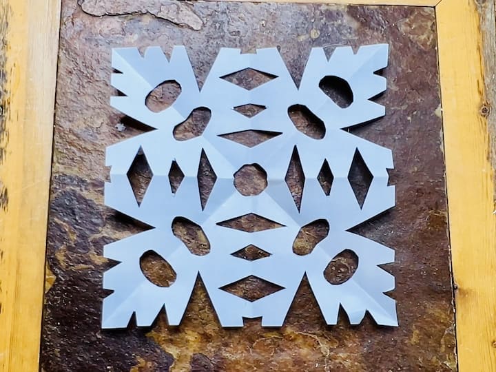 Once cutting is complete, unfold the paper to reveal your unique snowflake.