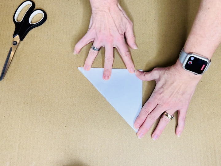 Fold the square sheet of paper back into a triangle.Fold the triangle in half, creating a smaller triangle.Fold it in half again.
