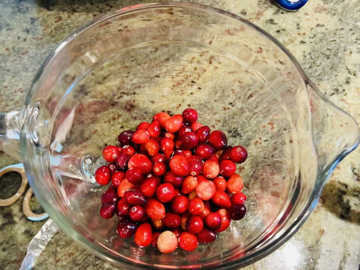 While the sugar mix is cooking, place two cups of fresh cranberries into a bowl. 