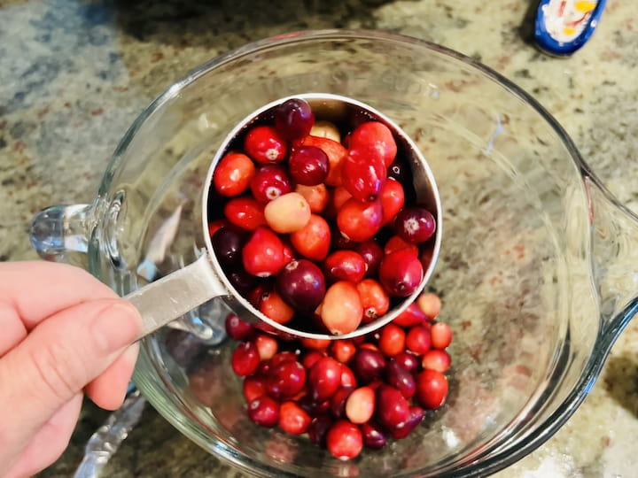 While the sugar mix is cooking, place two cups of fresh cranberries into a bowl. 