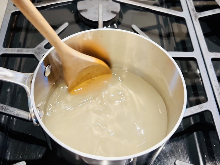 Start by placing two cups of water into a medium saucepan. Add two cups of sugar into the water and stir continuously over heat until the sugar is completely dissolved. This process creates a sweet and glossy simple syrup.
