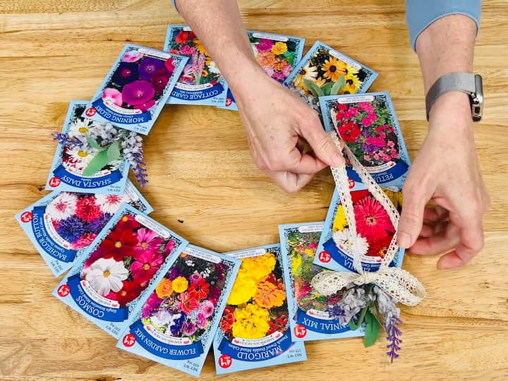 overhead shot showing the ribbon being glued on near flowers on seed packet wreath