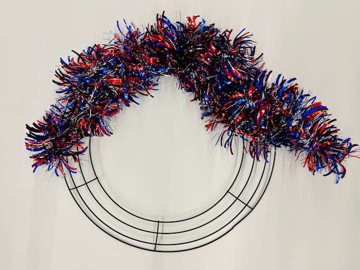 overhead shot showing step of diy summer wreath of wrapping the tinsel around the wreath form.