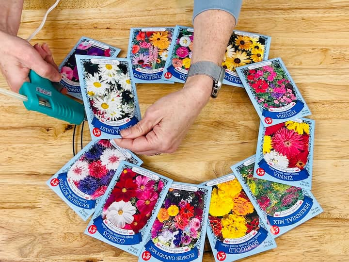 overhead shot of cool glue gun securing seed packets on wire wreath form