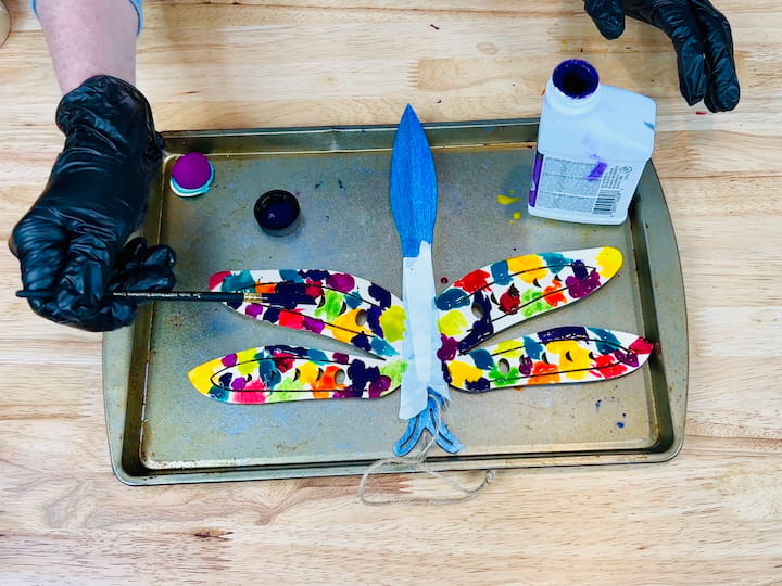 overhead shot of wings being painted on dragonfly in all colors