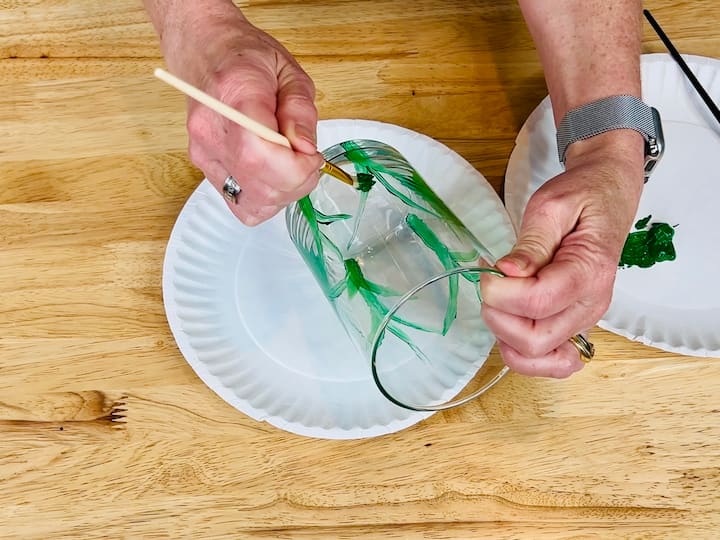 overhead shot of painting the green leaves on flower craft project with paintbrush