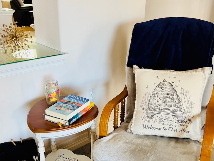 mason jar flower craft on side table with books beside sitting chair in the living room with a tea light candle burning inside