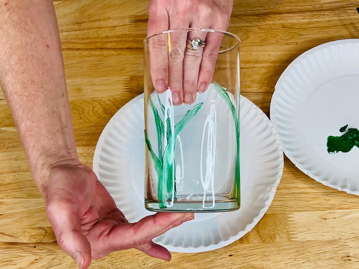 overhead shot of green flower stems on flower craft vase using paintbrush