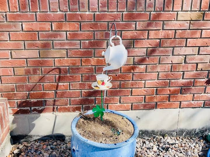 setting up flower pot for garden art with teapot dripping into teacup with crystal