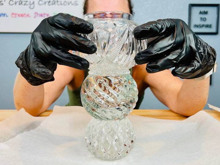 hands stacking three glass candle holders for snowman craft project