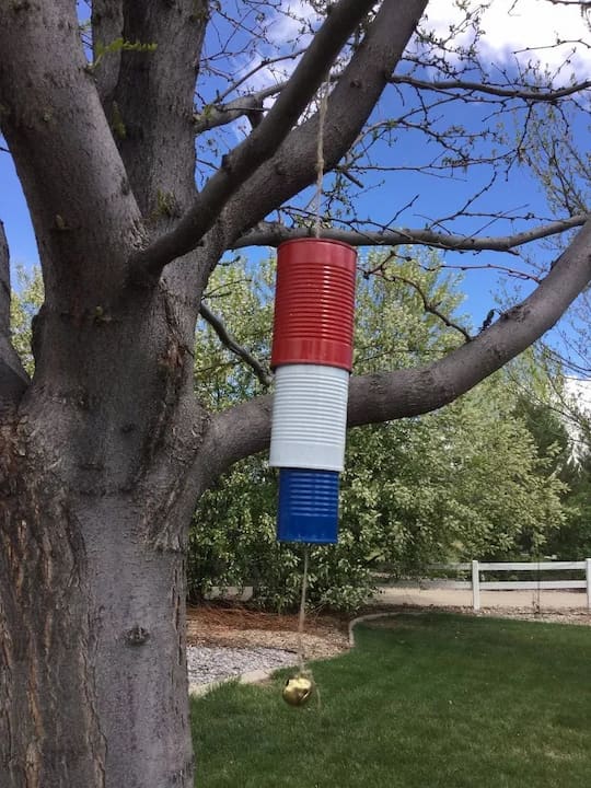 wind chime made from recycled tin cans hanging in tree for outdoor decor