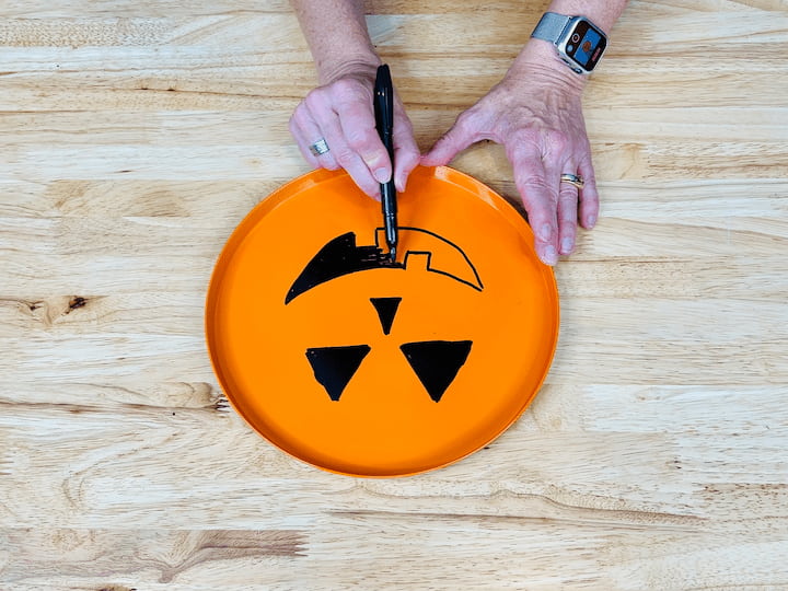 And I let both of those pans dry completely. Once they were dry, I brought them inside and I used a permanent marker to draw on a jack o lantern face on the orange one. 