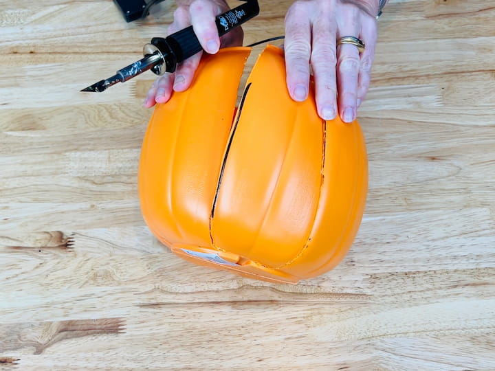 I marked two lines on either side of the back of the pumpkin so I'd know where I needed to cut next. I placed the hot knife tip onto my plaid wood burning tool, and then I was able to cut the back right off.