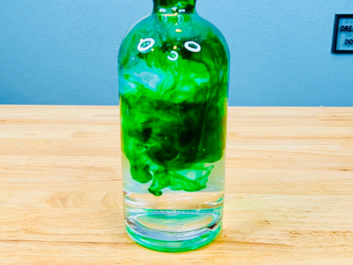 I've been saving this unique-shaped bottle, and I'm going to fill this one up with water too. I'm adding green food coloring to this one.