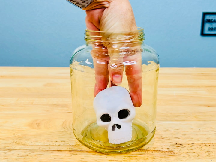 This is an old pickle jar and I'm just taking one of those squeezy skulls and placing it in the center of this one.