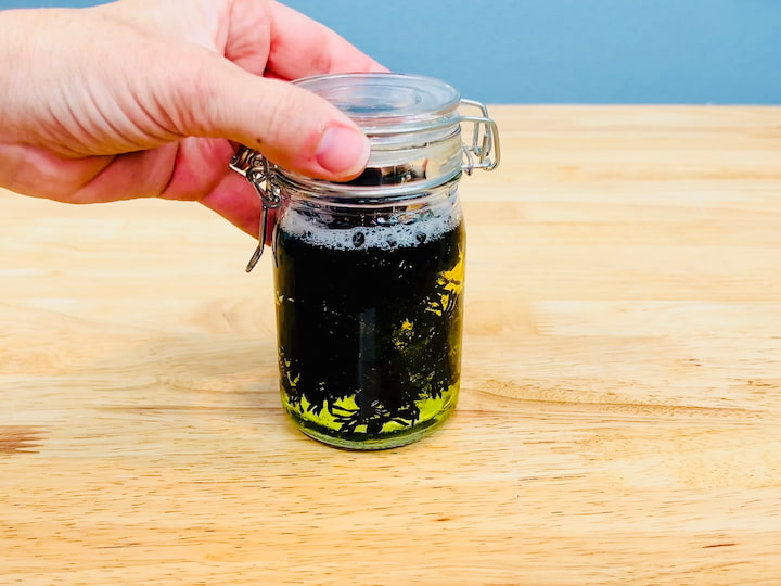 So I grabbed some dial soap that was bright yellow and I poured it into this jar. And I grabbed a bunch of confetti spiders and placed them into the jar with the soap. 