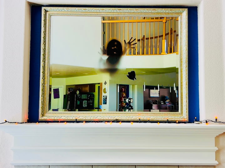 And I started by adding a strand of orange LED lights all the way around the mantel. Now I have a mirror above my mantel and I started by adding a creepy window cling to it as a focal point.