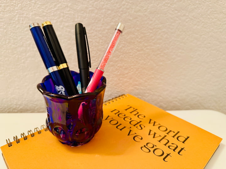 colored glass candle holder holding pens