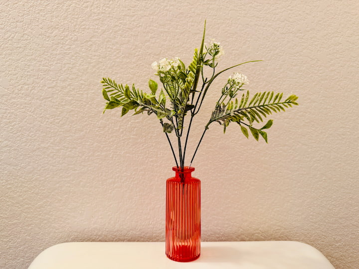 The colored glass bottle holding faux plant