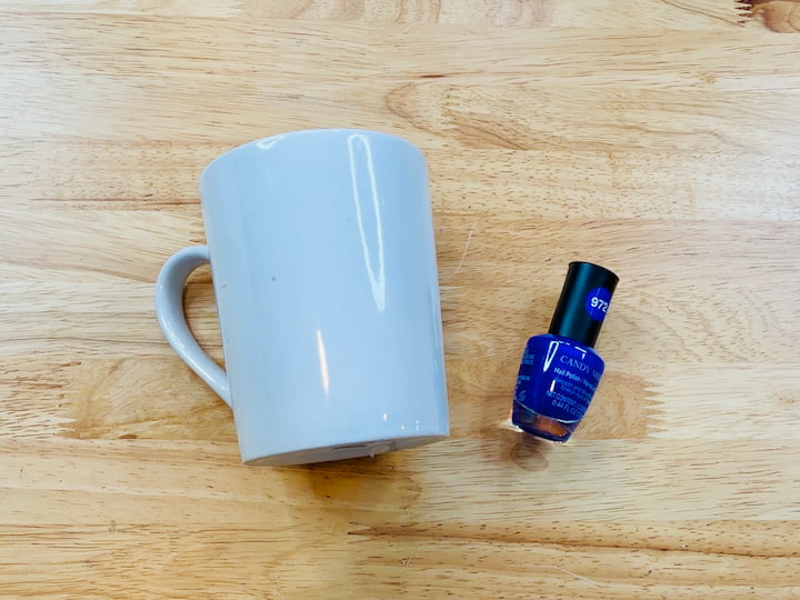 white mug and blue nail polish