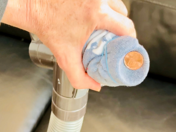Vacuum with sock on with a penny sucked in the sock