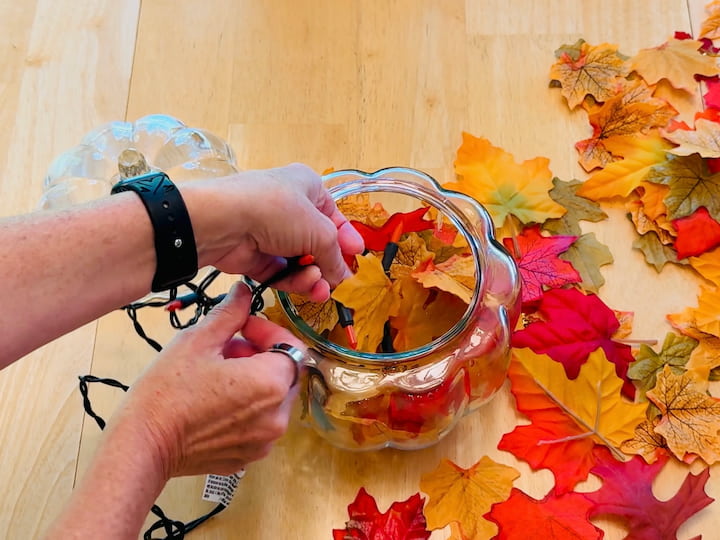 Adding leaves and lights into pumpkin jar