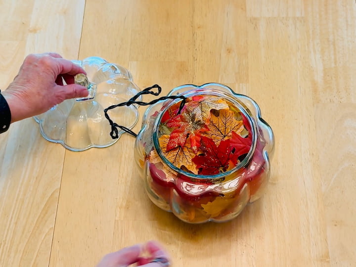 Filling pumpkin jar with leaves and lights