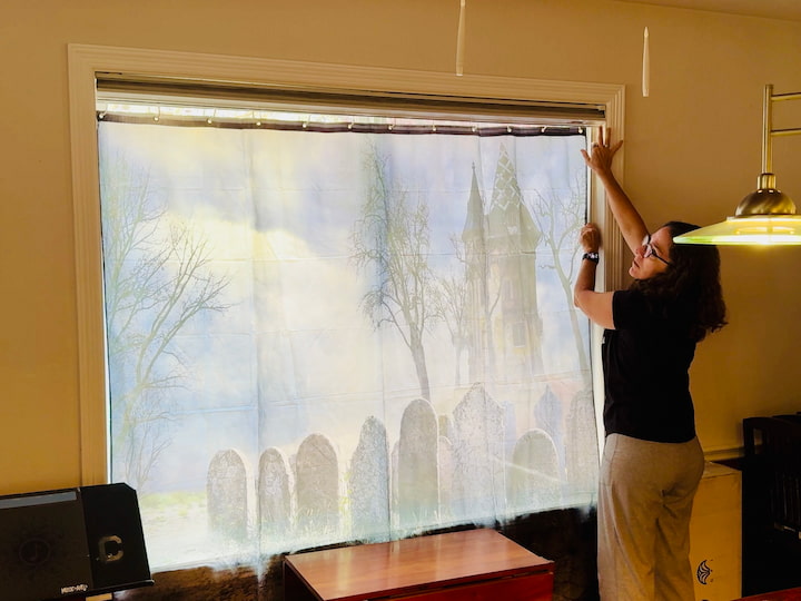 I hung a spooky graveyard shower curtain in the dining room window using a tension rod. During the day, the light shines through, and the whole scene glows.