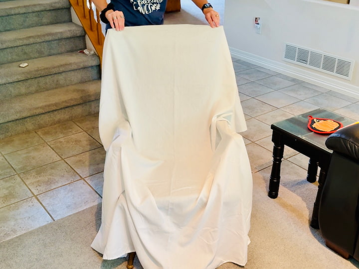 Chas draping a white sheet over a chair