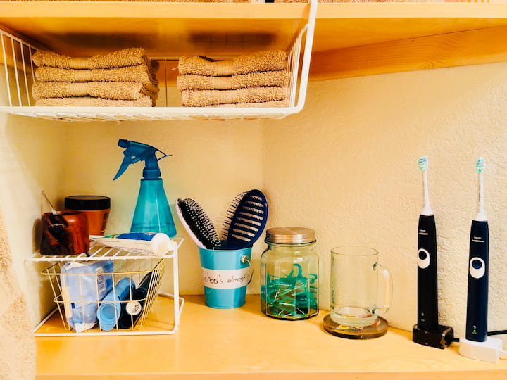 Shelf with organized bathroom supplies and created shelf via stacking organizer