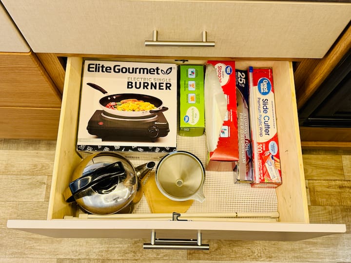 Coffee Corner: I placed my tea kettle and my small, collapsible drip coffee filter in this space. Since they are used daily, having them easily accessible is key.

The Roll Solution: Roll goods—like Saran wrap, storage baggies, and tin foil—can take up frustrating space. The key is finding a drawer deep enough to lay them flat or to store them upright using tension rods to keep them contained. This keeps them tidy and prevents them from rolling around while traveling.

Small Appliance Fit: This was also the perfect space to toss in a small crockpot. Remember, it’s like a puzzle—sometimes you have to change the direction you place an item to make it fit better!